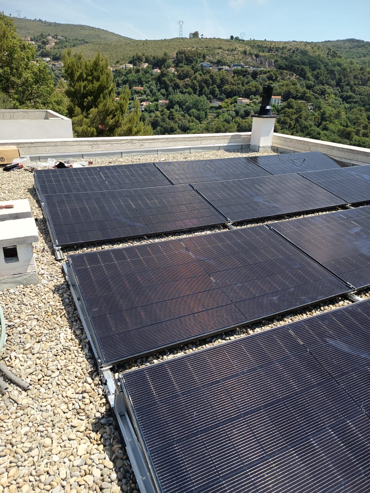 Panneaux solaires sur une toiture-terrasse plate, collines du Sud de la France en arrière-plan